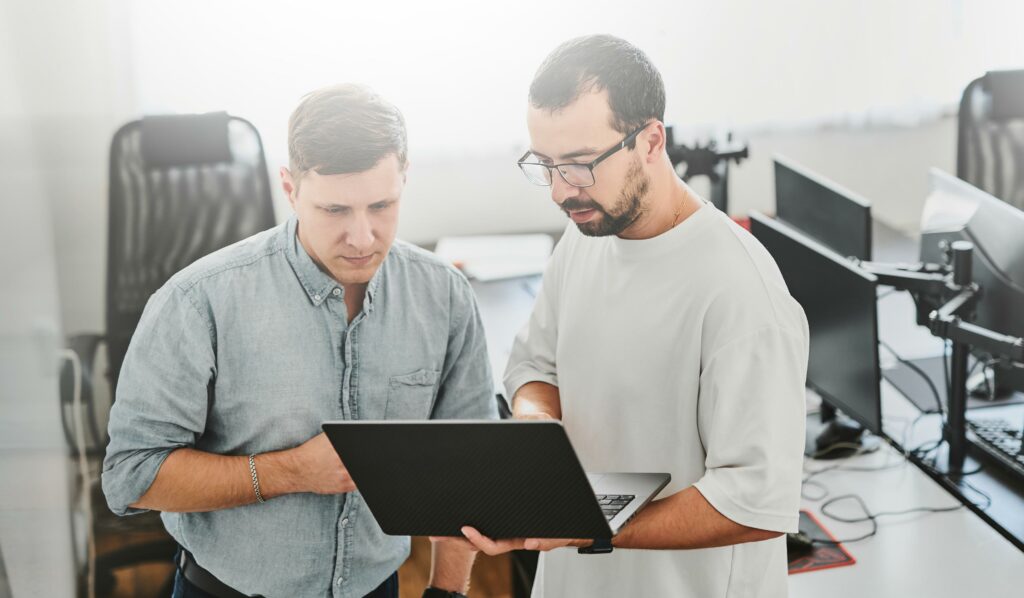 2 Männer stehen zusammen und machen eine Fehleranalyse mit einem Notebook